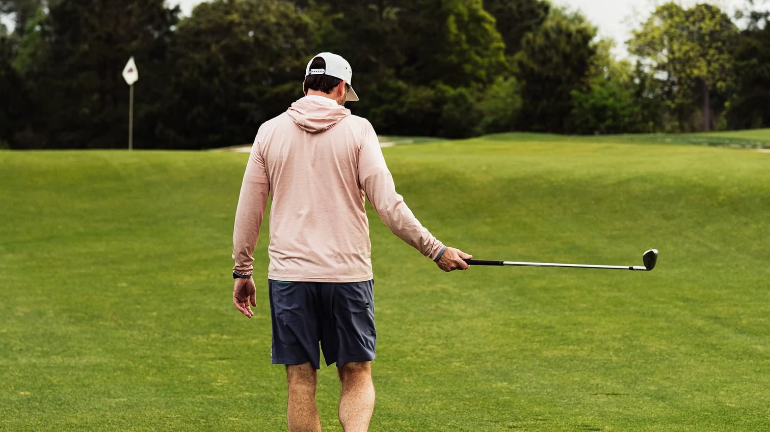 Man wearing Live Forever Golf attire walking on a golf course